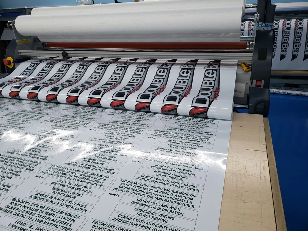 Printed equipment decals and safety labels rolling through a production laminator