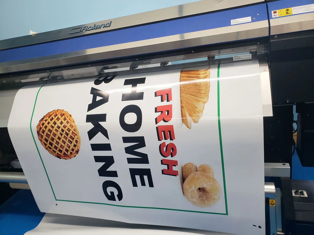 A large promotional banner being produced on a wide-format printer